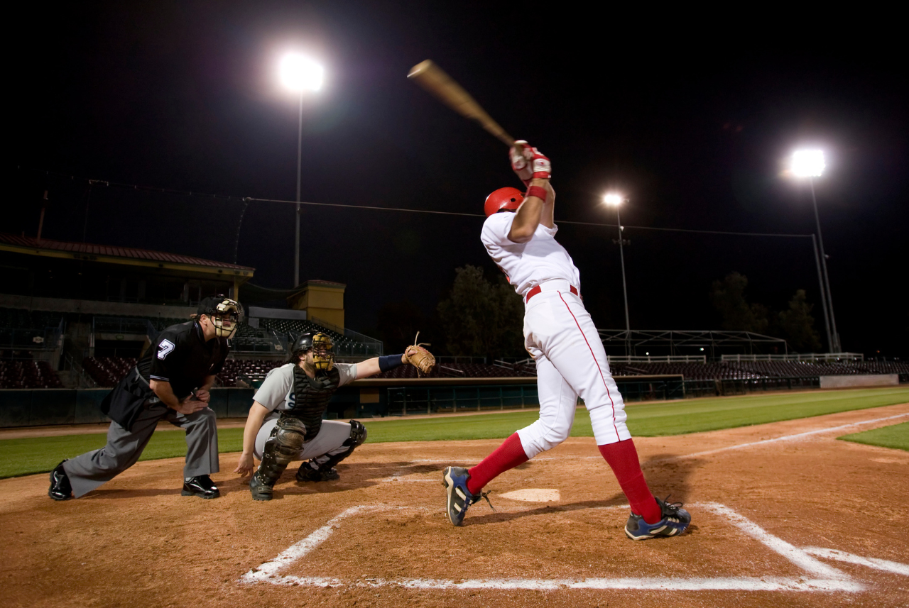 baseball player in red and white uniform hitting a ball at home plate